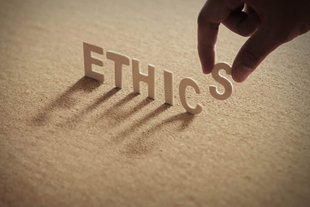 ethics wood word on compressed board with human's finger at s le